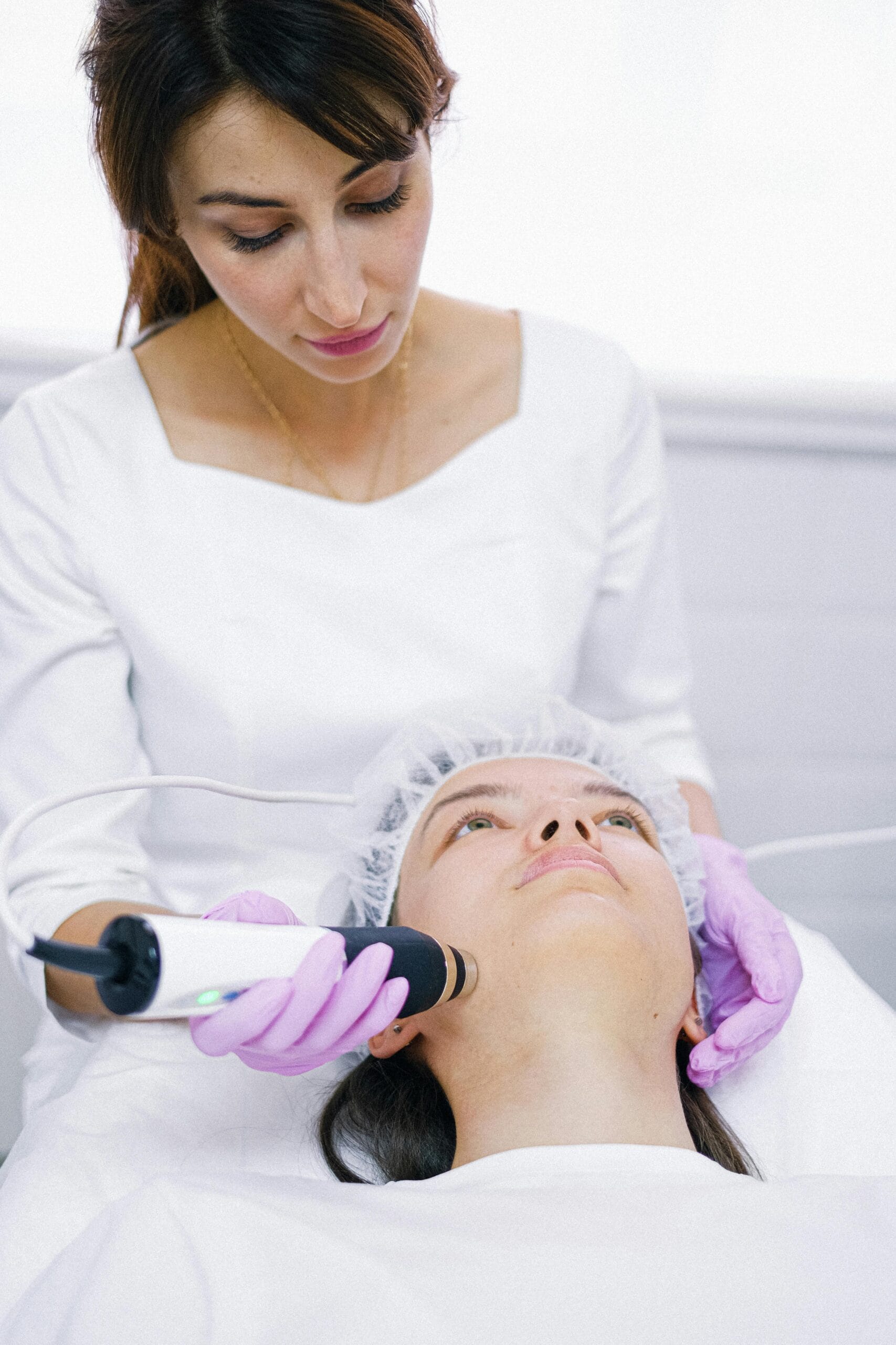 Aesthetician performs a laser skin care treatment on a patient in a clinic.